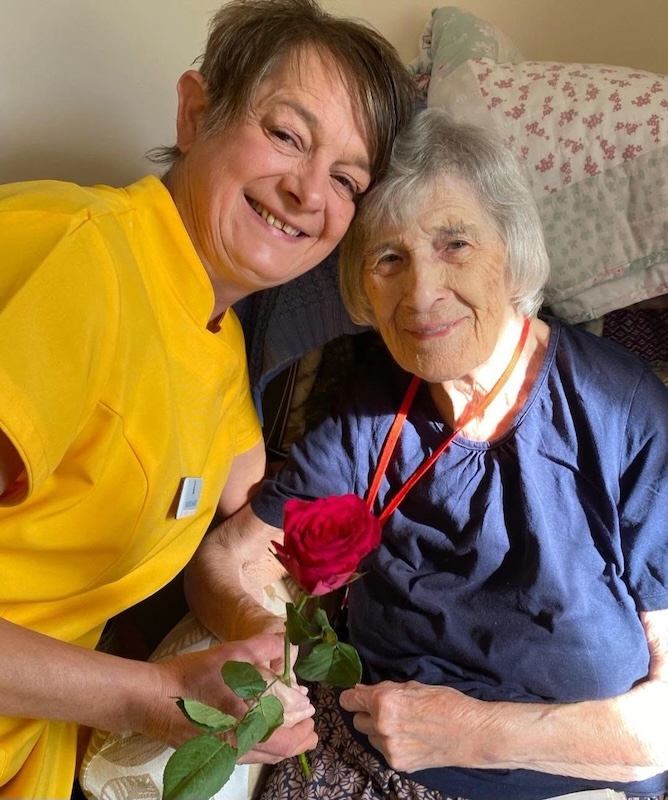 resident and carer smiling with rose